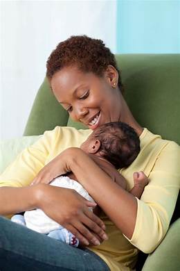 A mother holding her baby in front of the couch