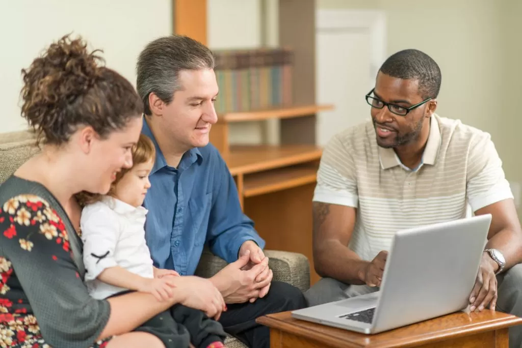 A family with a new born baby looking at a laptop