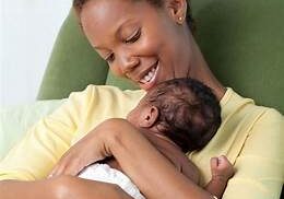 A mother holding her baby in front of the couch