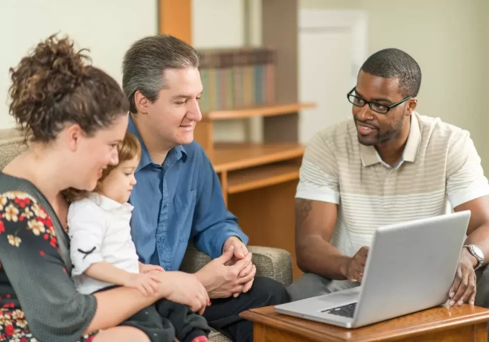 A family with a new born baby looking at a laptop